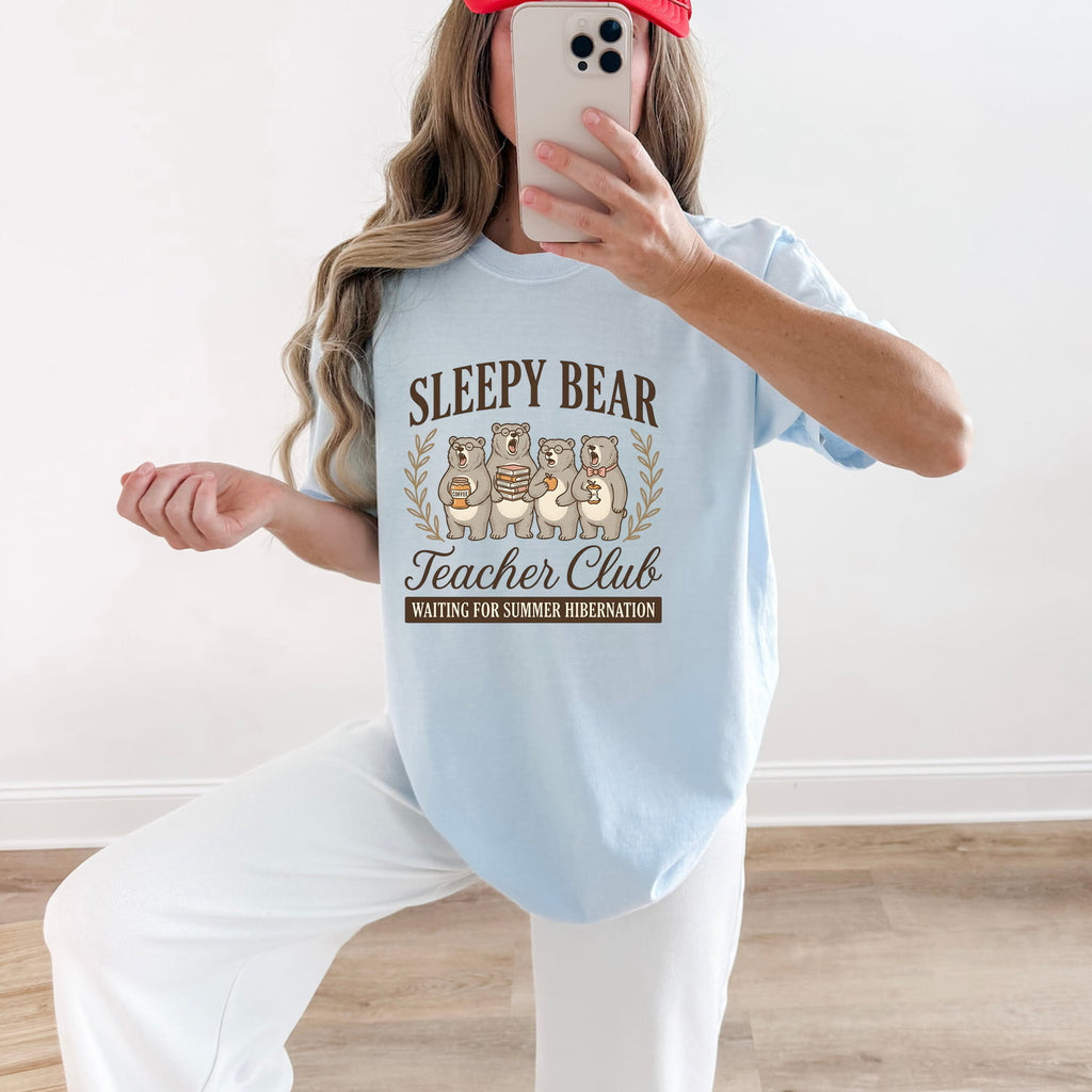 Sleepy Bear Teacher Club Text with an Iage of 4 Yawning Bears, and a humorous statement Waiting for Summer  Hibernation. The image shows the light blue Chambray color tshirt on a girl holding her phone up in front of her. 