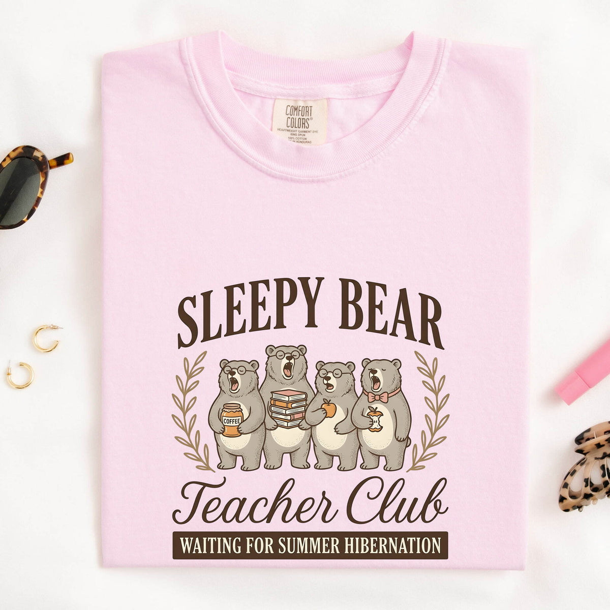 Sleepy Bear Teacher Club Text with an Iage of 4 Yawning Bears, and a humorous statement Waiting for Summer  Hibernation. The image shows the light blossom pink color shirt folded on a table.