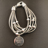 Faux leather bracelet with silver tone beads, a lobster clasp, and a stamped charm.